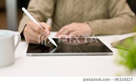 Woman in cozy sweater using stylus pen, drawing or writing on tablet screen, using digital tablet Woman in cozy sweater using stylus pen, drawing or writing on tablet screen, using digital tablet 96320827