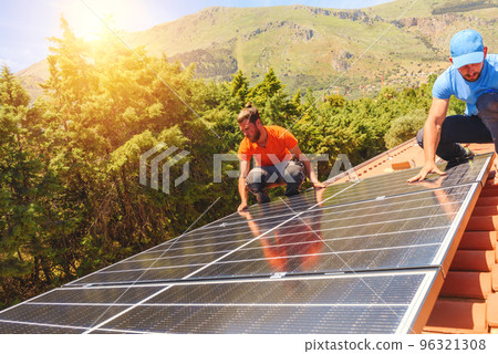 Workers assemble energy system with solar panel for electricity and hot water 96321308
