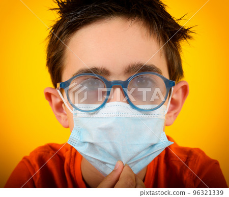Child with fogged lens due to face mask for covid-19 coronavirus. yellow background Child with fogged lens due to face mask for covid-19 coronavirus. yellow background 96321339