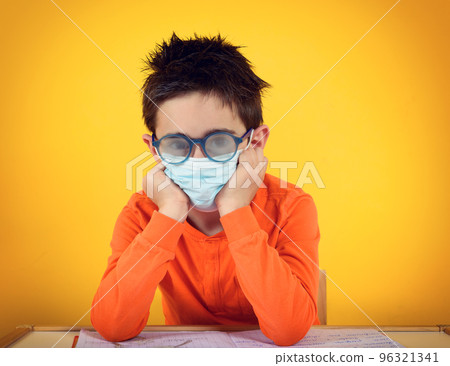 Child with fogged lens due to face mask for covid-19 coronavirus. yellow background 96321341