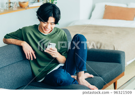 年輕人看著房間裡的智能手機 96321509