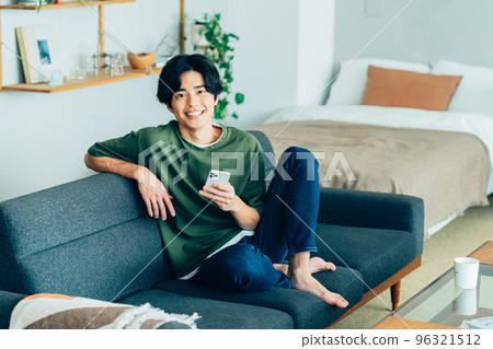 年輕人看著房間裡的智能手機 96321512
