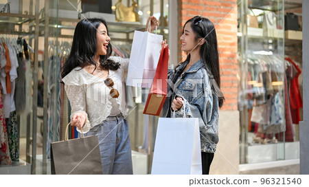 Attractive Asian women showing their shopping bags to each other, enjoy shopping Attractive Asian women showing their shopping bags to each other, enjoy shopping 96321540