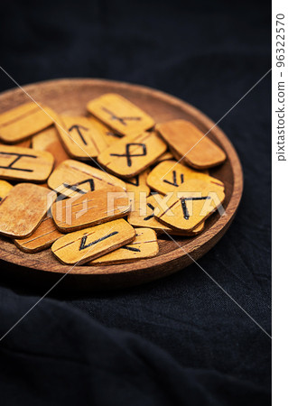 Handmade wooden runes on black fabric. Heap of Scandinavian runes for divination, close up. 96322570