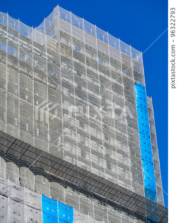 Building under construction wrapped blue and white protection safety net. Building under construction wrapped blue and white protection safety net. 96322793