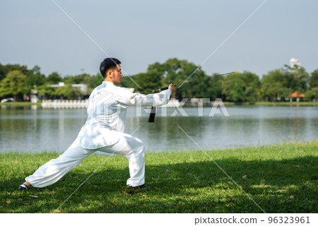 Young man practicing traditional Tai Chi Sword, Tai Ji in the park for healthy, traditional chinese martial arts concept on natural background . 96323961
