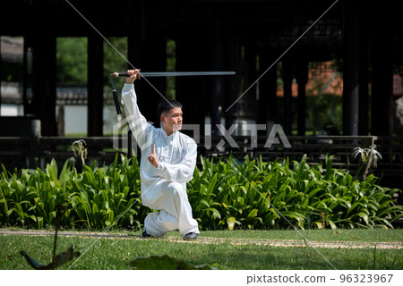 Young man practicing traditional Tai Chi Sword, Tai Ji in the park for healthy, traditional chinese martial arts concept on natural background . Young man practicing traditional Tai Chi Sword, Tai Ji in the park for healthy, traditional chinese martial arts concept on natural background . 96323967