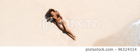 Top Aerial Drone View of Woman in Swimsuit Bikini Relaxing and Sunbathing on Beach White Sand 96324314