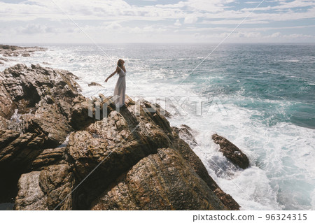 Romantic Bride, Brunette Girl in White Wedding Dress on Cliff Against Sea Background 96324315