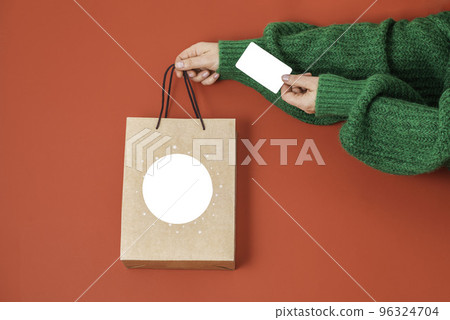 Xmas shopping concept. Woman's hands holding a gift bag and a credit card on a red background, Xmas shopping concept. Woman's hands holding a gift bag and a credit card on a red background, 96324704