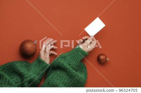 Christmas shopping concept. Flat lie hands in a green sweater with bonus card. Banner on a red background Christmas shopping concept. Flat lie hands in a green sweater with bonus card. Banner on a red background 96324705