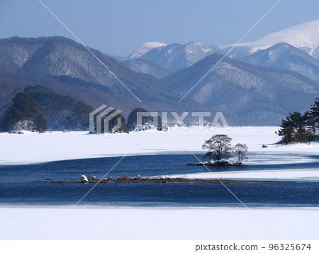 Urabandai in winter, Lake Akimoto. A beautiful collaboration of unfrozen blue lake water, white snowfields, and scattered island trees Urabandai in winter, Lake Akimoto. A beautiful collaboration of unfrozen blue lake water, white snowfields, and scattered island trees 96325674