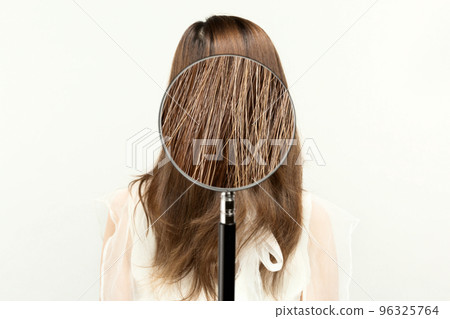 Magnifying a woman's hair with a loupe. 96325764