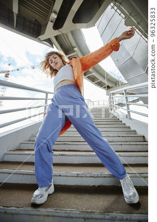 Dynamic full length shot of young woman dancing outdoors 96325833