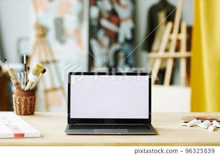 Workplace of digital artist with laptop and bunch of paintbrushes 96325839