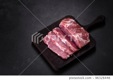 Fresh piece of raw pork with spices, salt and herbs on a wooden cutting board 96326446
