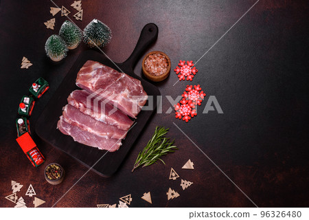 Fresh piece of raw pork with spices, salt and herbs on a wooden cutting board 96326480