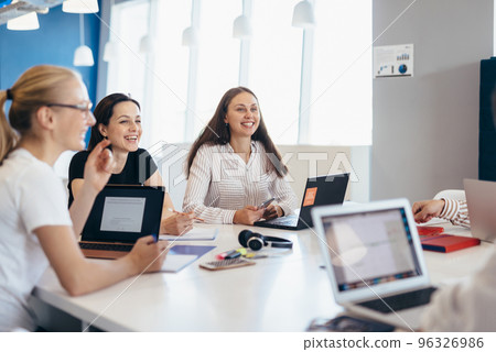 Young smiling women sitting at table in class or job. Young smiling women sitting at table in class or job. 96326986