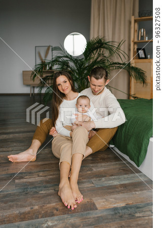 Stylish young family with a baby are sitting on the bedroom floor and enjoying happy moments 96327508