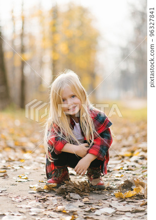 One little girl in the Park. Sunny autumn day in the city Park. Orange-yellow calm mood. Happy childhood 96327841