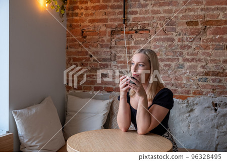 Beautiful Caucasian woman dreaming about something while sitting with a cup of coffee in modern cafe 96328495