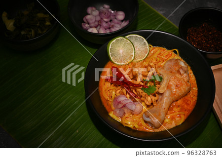 Khao Soi Kai, Noodles curry soup with chicken drumstick, fried chilies, lime and shallot slides 96328763