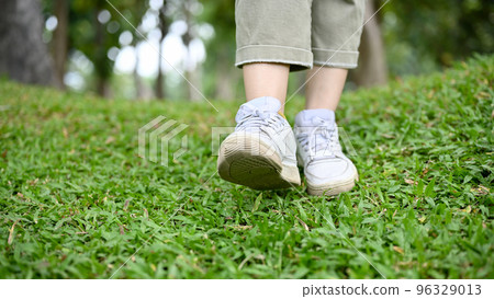 A hipster woman in casual clothes and white sneakers strolling in the garden. cropped A hipster woman in casual clothes and white sneakers strolling in the garden. cropped 96329013