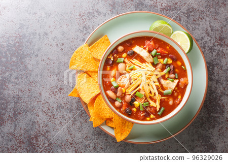 Chicken taco soup cooked in fragrant broth with beans, corn, tomatoes served with lime and tortilla chips close-up in a plate. Horizontal top view Chicken taco soup cooked in fragrant broth with beans, corn, tomatoes served with lime and tortilla chips close-up in a plate. Horizontal top view 96329026
