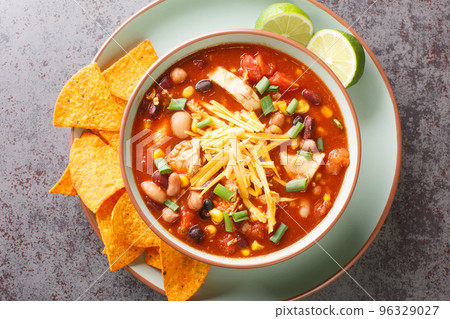 Chicken Taco Soup with black bean, corn kernels, tomatoes topped with cheddar cheese in green bowl, horizontal top view Chicken Taco Soup with black bean, corn kernels, tomatoes topped with cheddar cheese in green bowl, horizontal top view 96329027