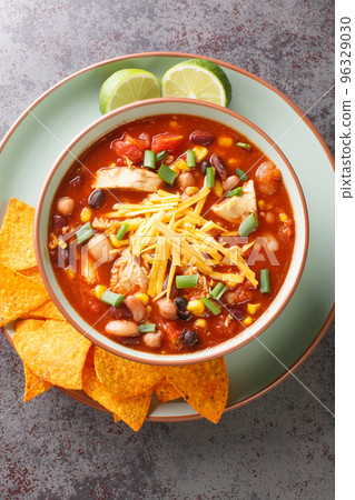 Taco chicken soup served with lime and tortilla chips close-up in a plate. Vertical top view Taco chicken soup served with lime and tortilla chips close-up in a plate. Vertical top view 96329030