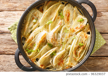 Baked fennel root with parmesan cheese and bechamel sauce close-up in a frying pan. Horizontal top view Baked fennel root with parmesan cheese and bechamel sauce close-up in a frying pan. Horizontal top view 96329037