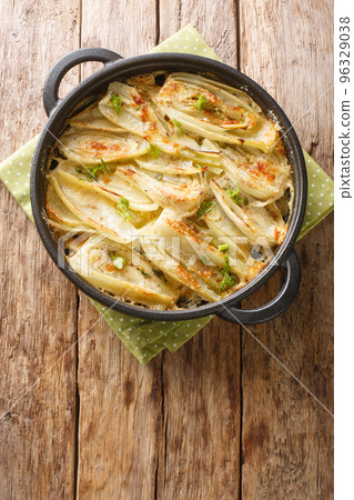 Fennel gratin. Baked fennel in parmesan bechamel sauce closeup on the wooden table. Vertical top view 96329038
