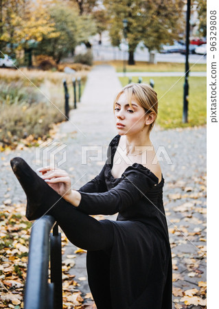 Ballerina Dancing in autumn city street, Modern Ballet Dancer in black dress, Pointe Shoes outdoors. Ballerina stretches, daily ballet stretching routine Ballerina Dancing in autumn city street, Modern Ballet Dancer in black dress, Pointe Shoes outdoors. Ballerina stretches, daily ballet stretching routine 96329808