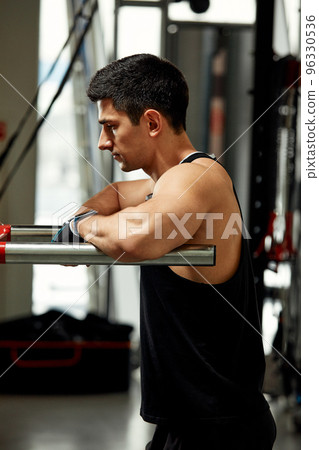 Strong muscular man doing push-ups on uneven bars in gym. Workout lifestyle concept. Strong muscular man doing push-ups on uneven bars in gym. Workout lifestyle concept. 96330536