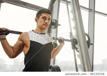 sport, bodybuilding, lifestyle and people concept - young man with barbell flexing muscles and making shoulder press lunge in gym sport, bodybuilding, lifestyle and people concept - young man with barbell flexing muscles and making shoulder press lunge in gym 96330546