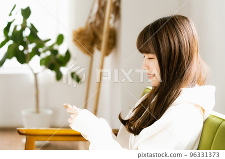 一位看著智能手機感到疲倦的年輕女性 96331373