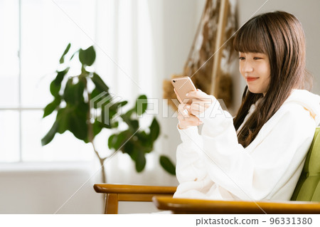 一位看著智能手機感到疲倦的年輕女性 96331380