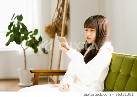 一位看著智能手機感到疲倦的年輕女性 96331391