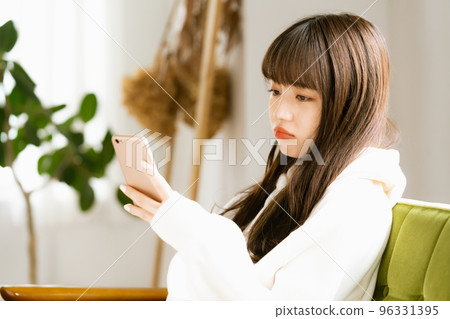 一位看著智能手機感到疲倦的年輕女性 96331395