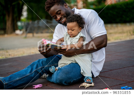 Young man teaching his daughter to read Young man teaching his daughter to read 96331855