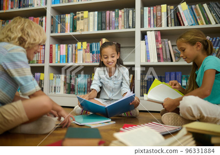 Group of schoolkids having a lesson of literature in the library 96331884