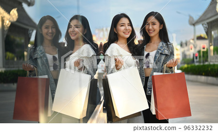 Two trendy beautiful women with shopping bags standing near showcase in city street. Shopping, tourism and lifestyle concept 96332232