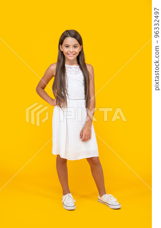 happy teen child in white dress standing on yellow background 96332497
