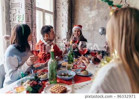 People celebrating sitting at the table, clinking glasses. Christmas or New Year eve. 96332971