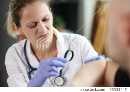 Female doctor examinning male patient at consultation in hospital. 96333445