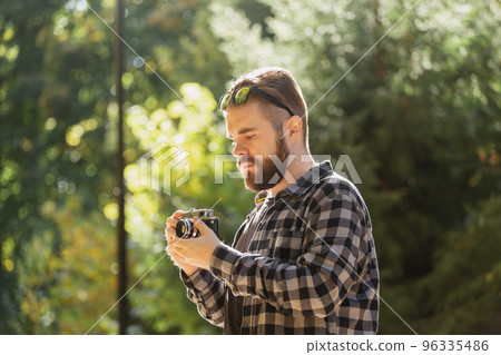 Man photographer taking picture with vintage camera on city green park copy space and place for text - leisure activity and hobby concept Man photographer taking picture with vintage camera on city green park copy space and place for text - leisure activity and hobby concept 96335486