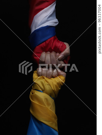 Russian flag and Ukrainian flag on a black background. Russian flag and Ukraine flag in hands showing symbol of struggle war political struggle political expressions Civil wars and territory conflict. Russian flag and Ukrainian flag on a black background. Russian flag and Ukraine flag in hands showing symbol of struggle war political struggle political expressions Civil wars and territory conflict. 96337004
