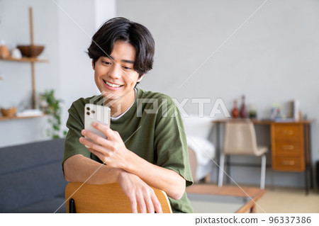 一個年輕人在家看他的智能手機 一個年輕人在家看他的智能手機 96337386