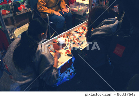 受市集夜市燈光的邀請，他嘗試了撈金魚。 96337642