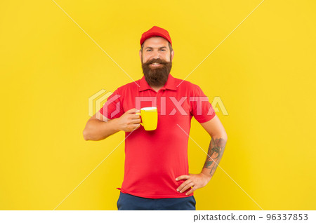Happy bearded man in casual red cap and tshirt holding mug yellow background, tea Happy bearded man in casual red cap and tshirt holding mug yellow background, tea 96337853